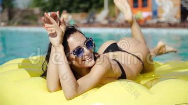 穿比基尼的女人在度假期间在游泳池里喝鸡尾酒享受夏日阳光和晒黑。 上景。 游泳的女人